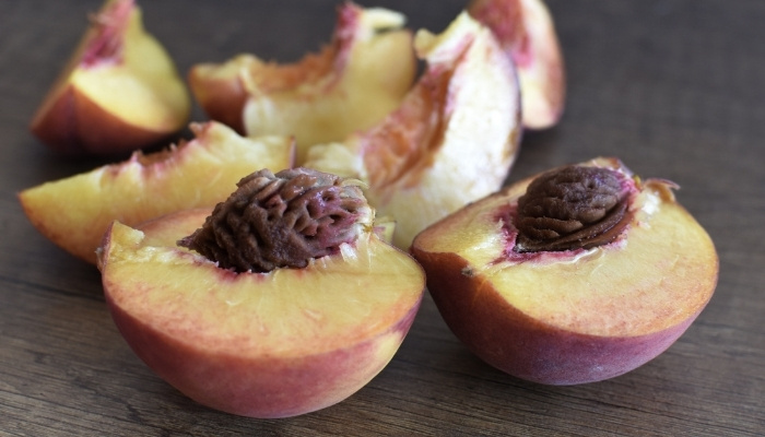 Several peaches sliced open to remove the pits.